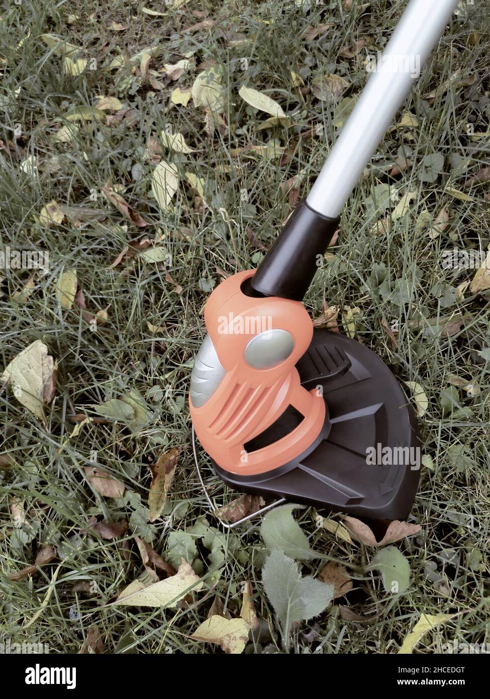 Appareils électroménagers : tondeuse-tondeuse pour couper des pelouses sur des batteries rechargeables.Présenté sur un fond d'herbe et de feuilles, vue avant, Banque D'Images