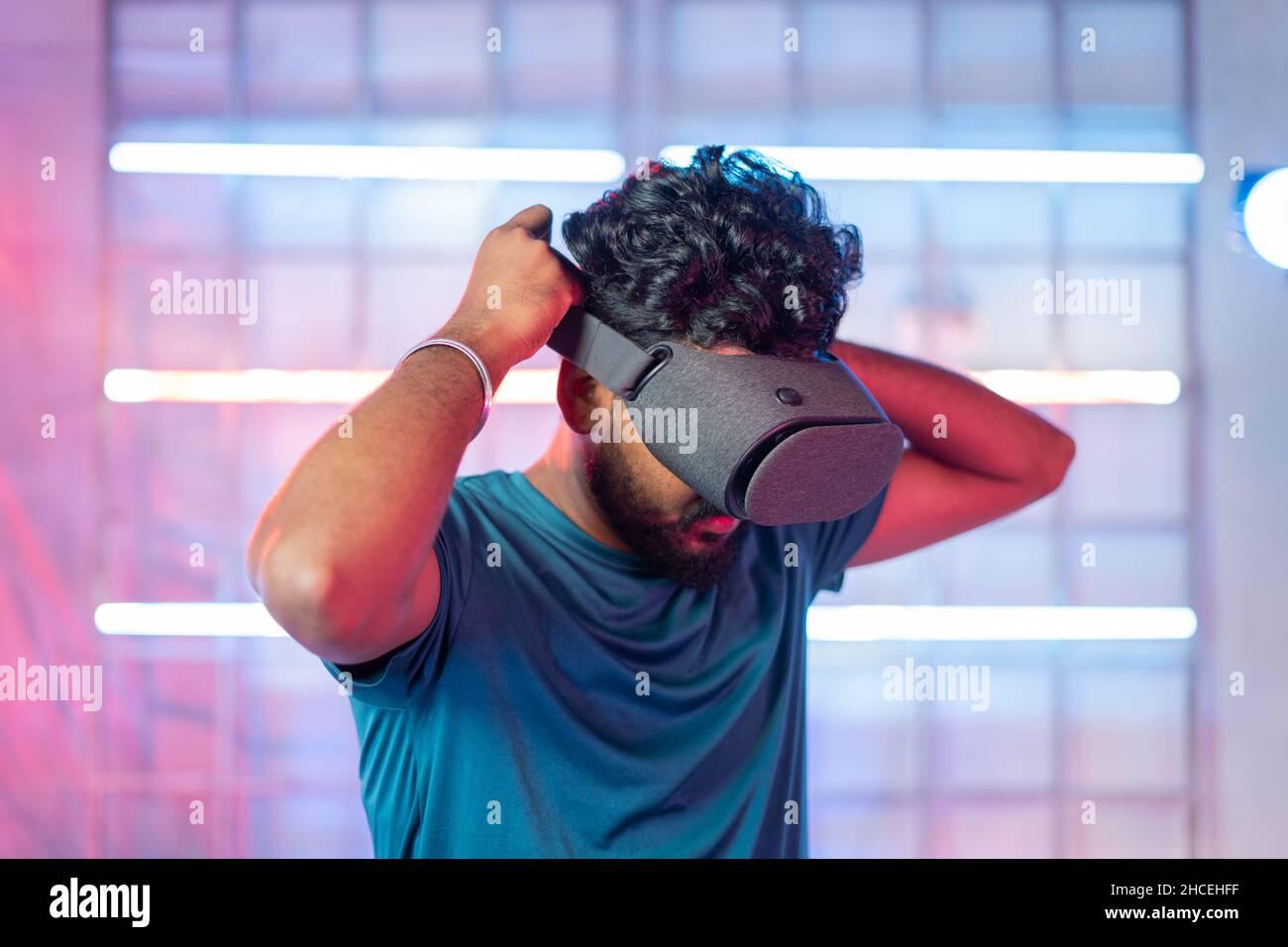 Joueur professionnel portant VR by avec mobile dans le micro-casque avant de jouer - concept de technologie de jeu moderne montrant sur fond de néon Banque D'Images