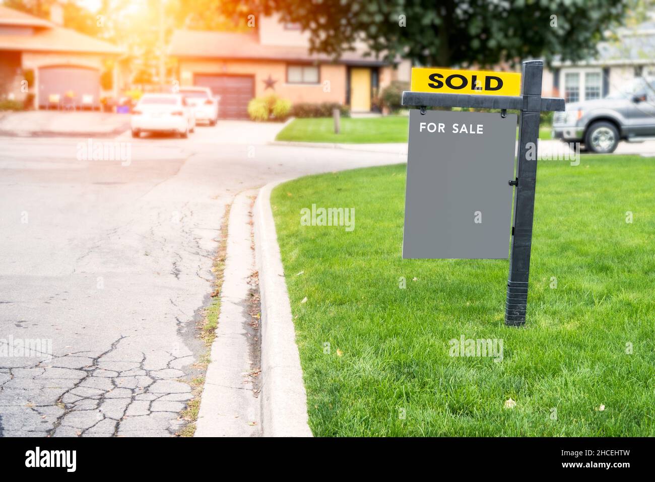 Panneau immobilier vierge sur une pelouse en face d'une maison vendue Banque D'Images