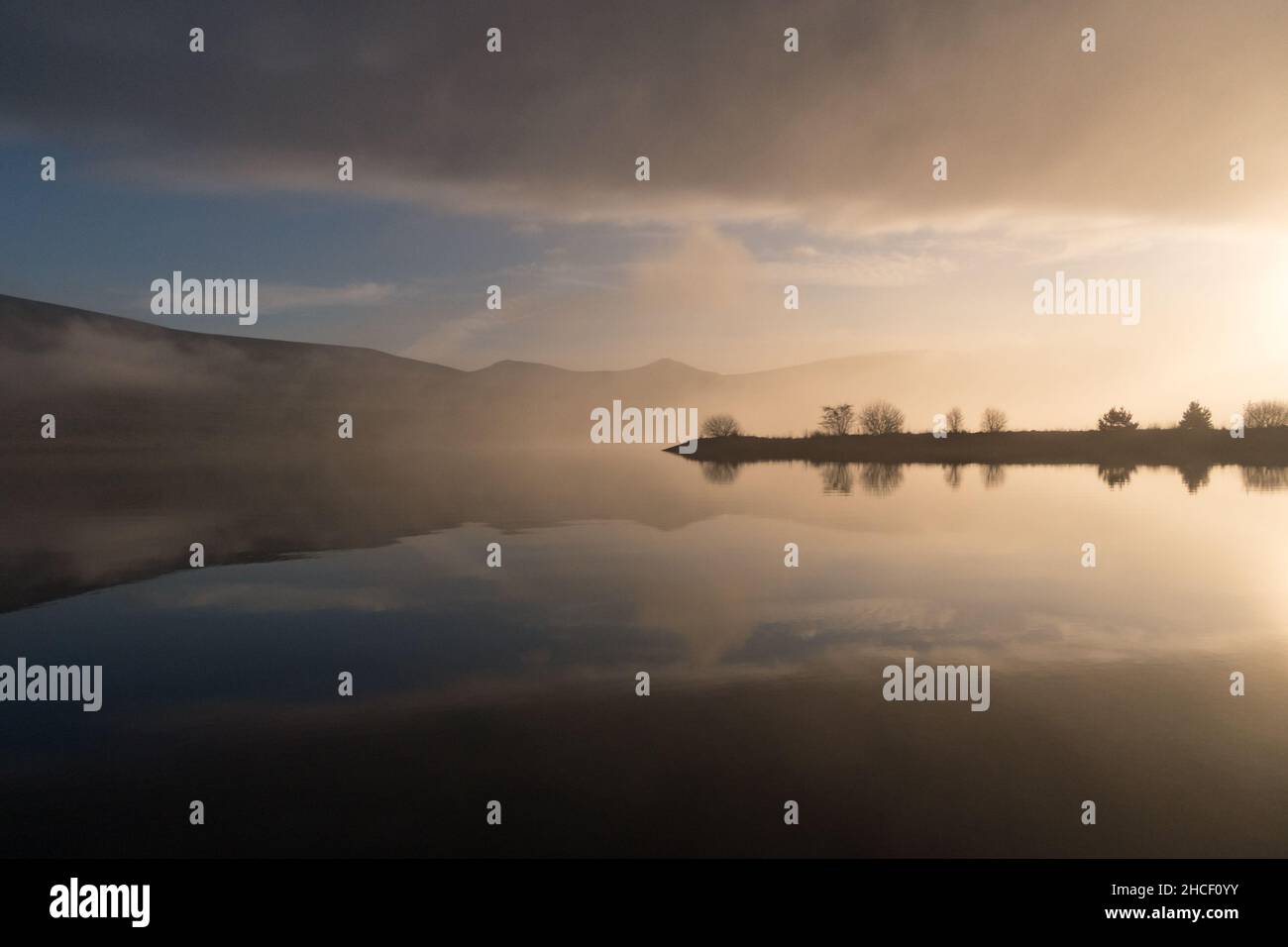 Les collines et les nuages se reflètent dans l'eau du réservoir lors d'une journée d'hiver Banque D'Images