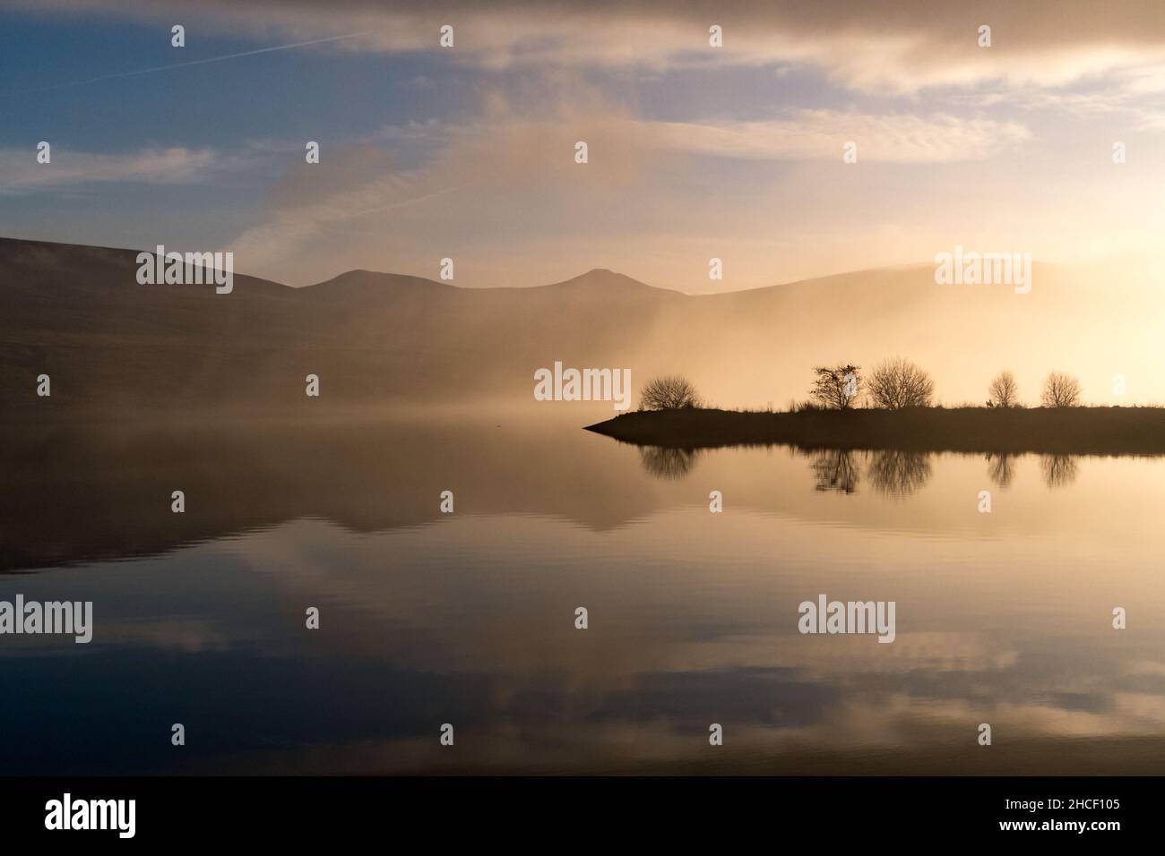 Les collines et les nuages se reflètent dans l'eau du réservoir lors d'une journée d'hiver Banque D'Images