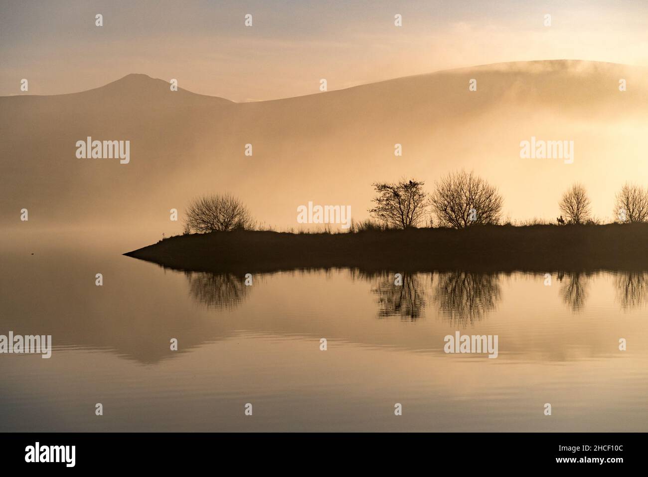 Les collines et les nuages se reflètent dans l'eau du réservoir lors d'une journée d'hiver Banque D'Images