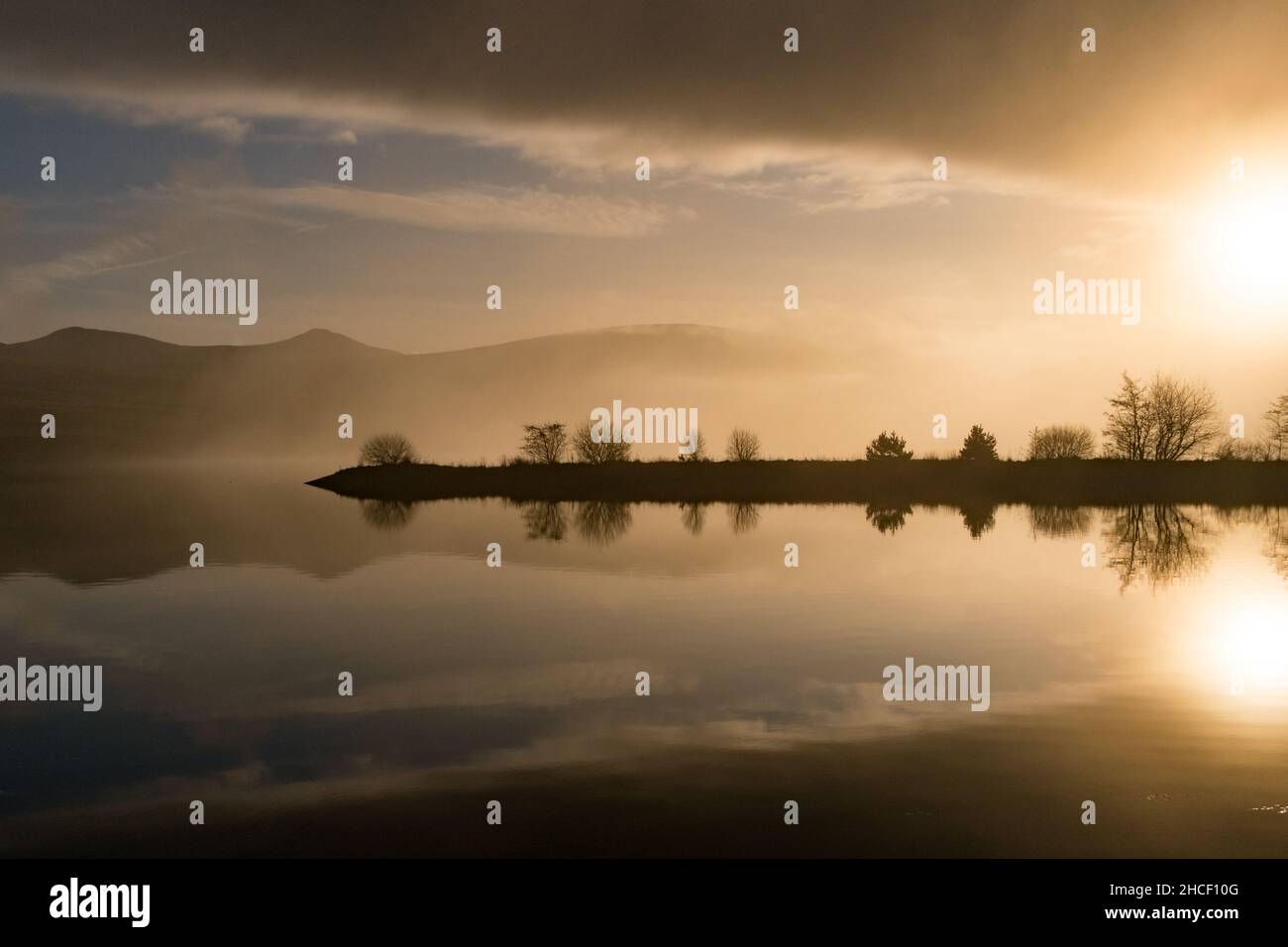 Les collines et les nuages se reflètent dans l'eau du réservoir lors d'une journée d'hiver Banque D'Images