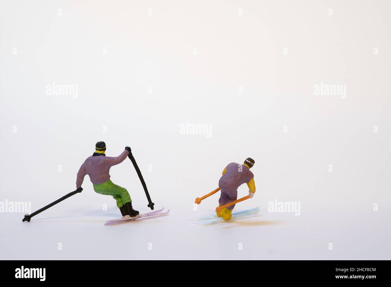 Skieurs miniatures en action - fond blanc, espace de copie Banque D'Images