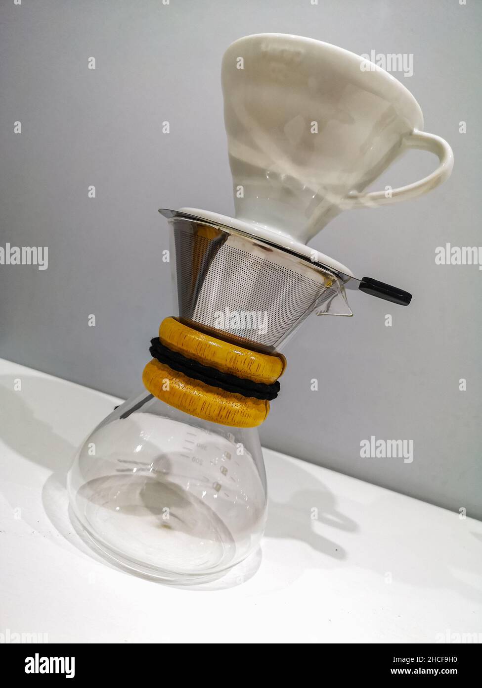 Petit chemex vitreux avec manche en bois et filtre en acier avec égouttoir en porcelaine Banque D'Images