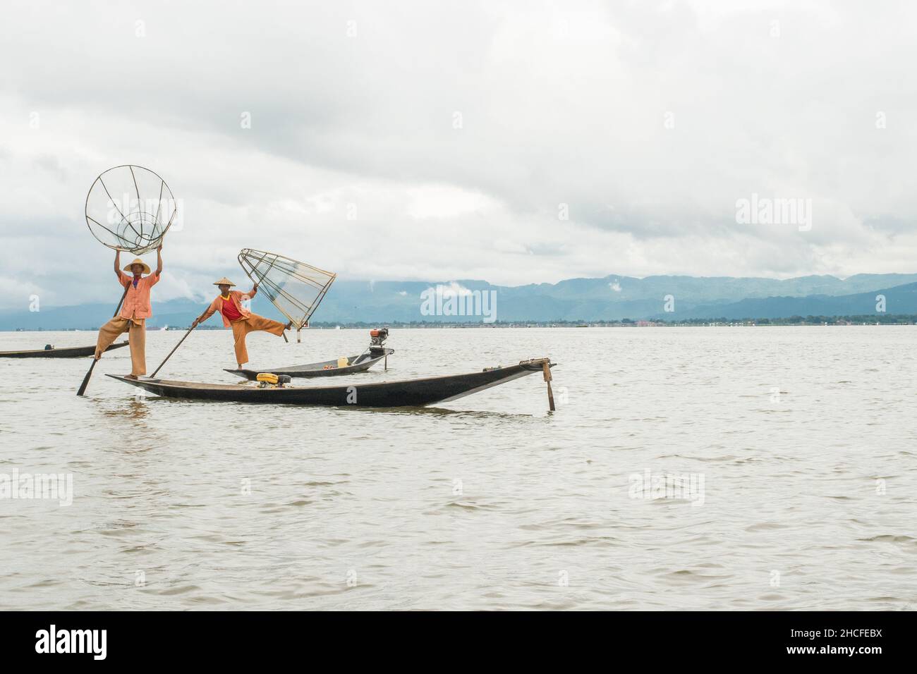 Pêcheur birman local posant pour des photos avec son filet, l'équilibrage et le bateau de pilotage avec un pied. Banque D'Images