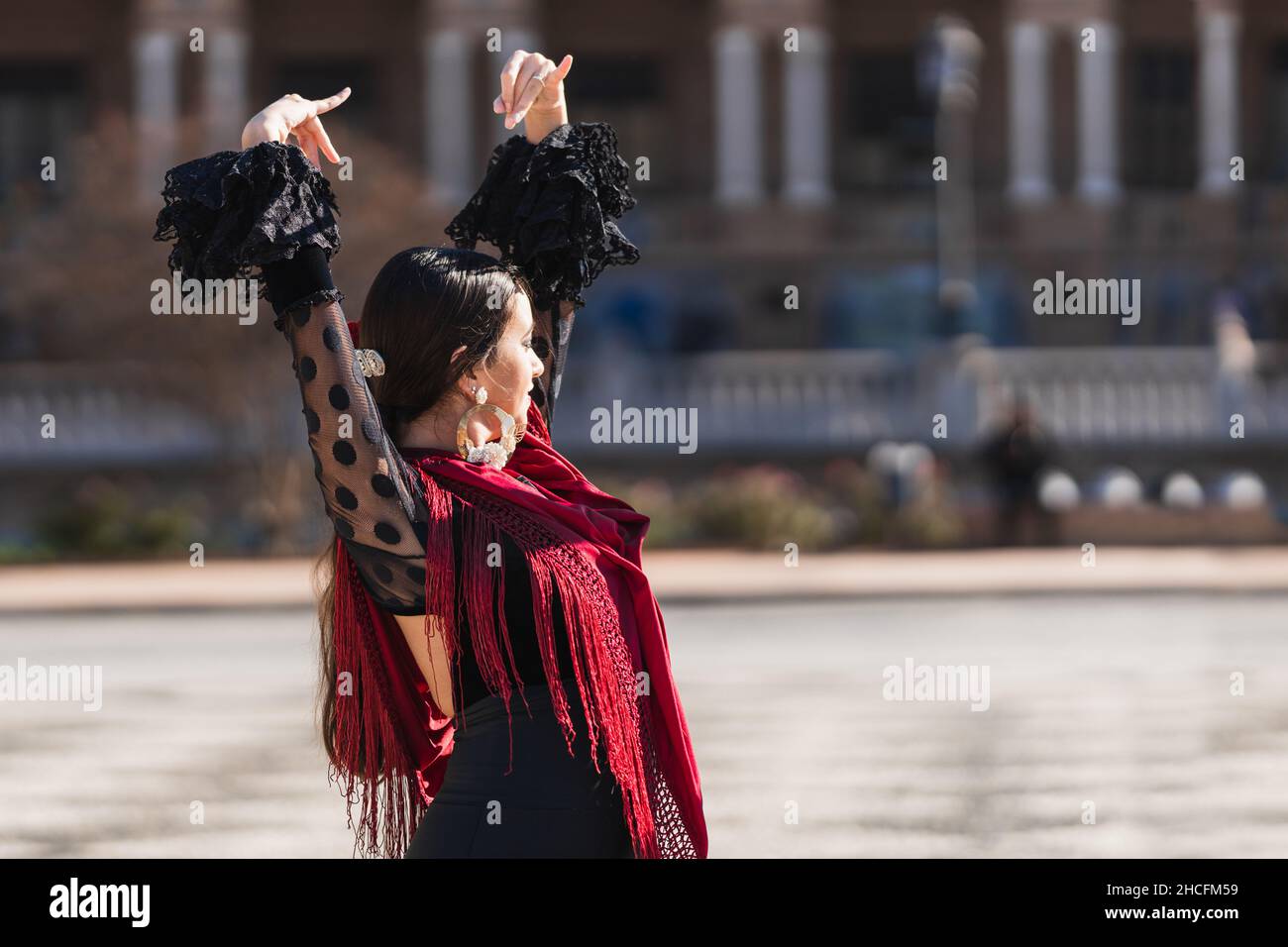 Femme en tenue de flamenco levant les bras tout en dansant à l'extérieur Banque D'Images