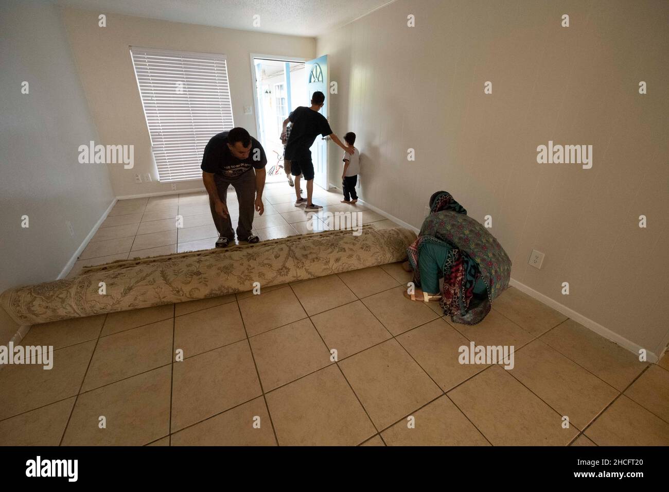 Austin Texas USA, octobre 2021: Les membres d'une famille afghane déroulent un tapis donné dans le salon de leur nouvelle maison dans un complexe d'appartements près du centre-ville.Les réfugiés fuyant la tourmente en Afghanistan continuent d'être réinstallés au Texas, avec de nombreux hommes célibataires et de grandes familles avec des enfants qui déménagent dans des appartements à travers Austin.Les groupes religieux et autres groupes à but non lucratif ont intensifié leurs efforts pour coordonner les efforts visant à fournir des maisons à des centaines de réfugiés.©Bob Daemmrich Banque D'Images