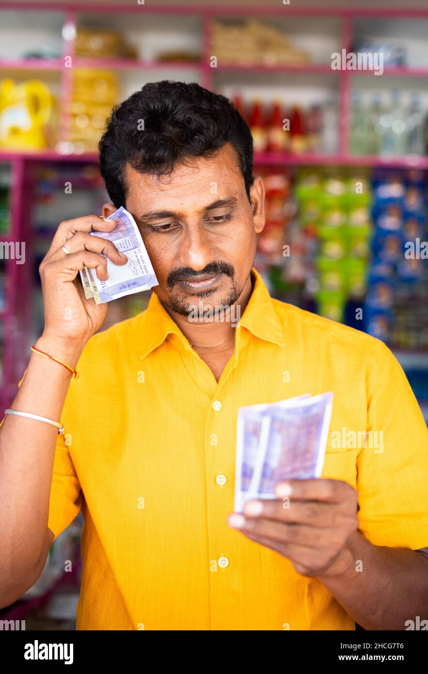 Portrait tourné de Kirana inquiet ou triste marchand d'épicerie comptant l'argent au magasin de détail - concept de faible ou de perte dans les affaires, la faillite et le prêt Banque D'Images