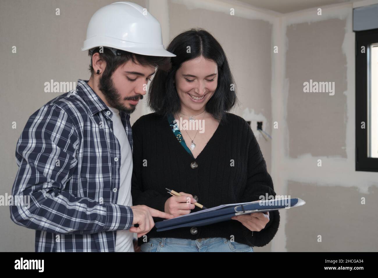 Une jeune femme signe un document pour acheter une maison en construction. Banque D'Images