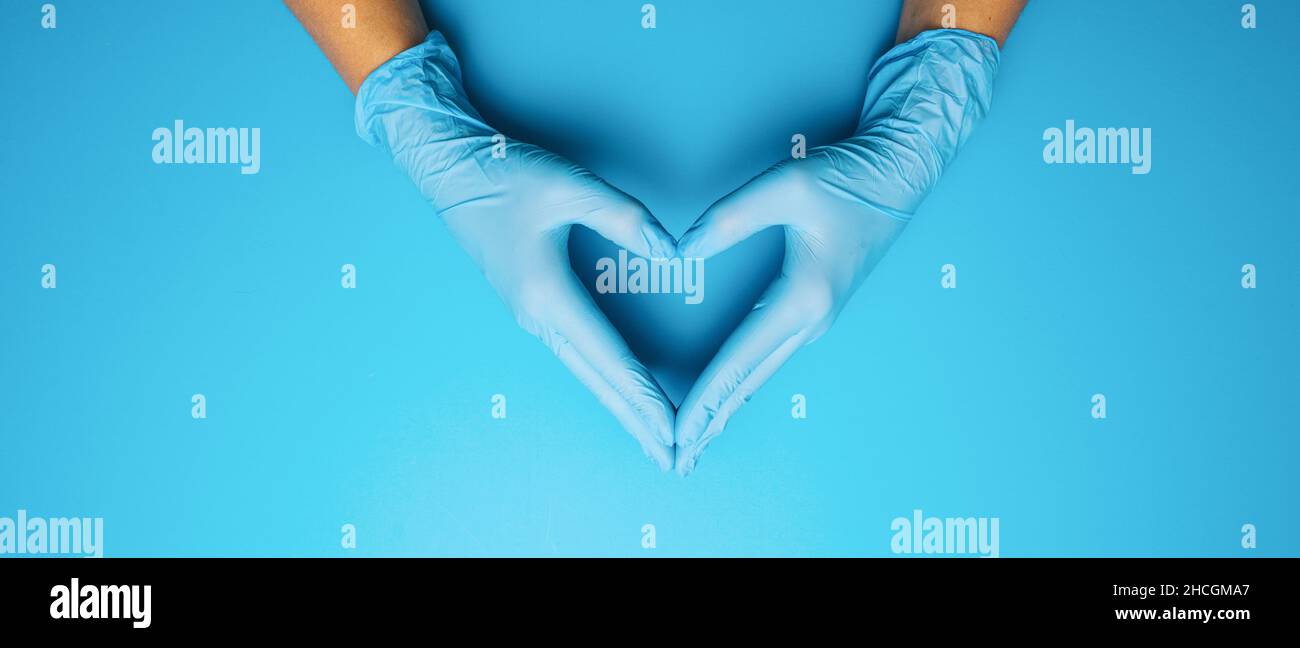 Médecin mains dans des gants montrant un masque médical sur fond bleu.Mesures préventives pour protéger contre l'infection par le virus Covid-19 Corona. Banque D'Images
