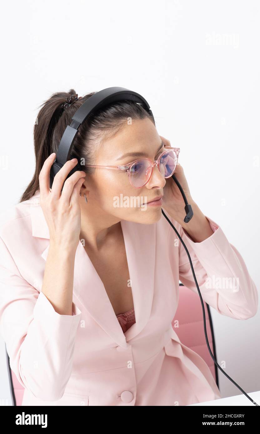 Angleterre, Royaume-Uni.2021. Femme portant une veste rose pour régler le casque dans un environnement de bureau. Banque D'Images