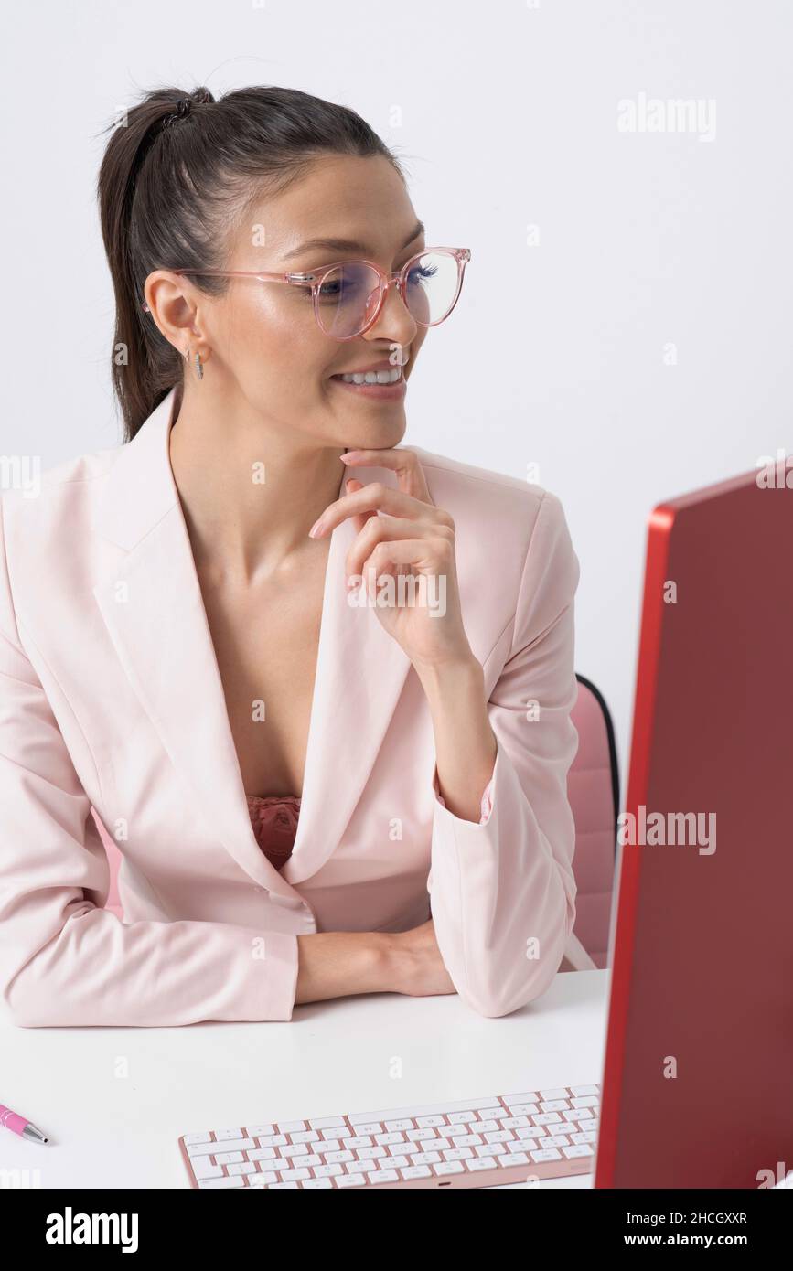 Angleterre, Royaume-Uni.2021. Belle employée de bureau portant des lunettes et regardant l'écran d'ordinateur. Banque D'Images