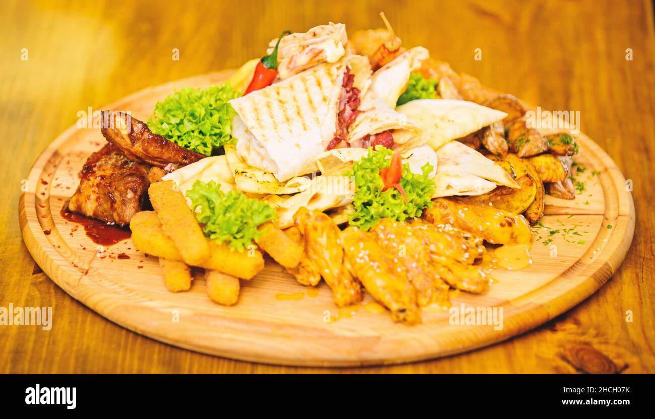 En-cas à haute teneur en calories pour les amis de groupe.Délicieux en-cas.Restaurant.En-cas pour la bière.Planche en bois avec beaucoup de frites bâtonnets de poisson burrito Banque D'Images