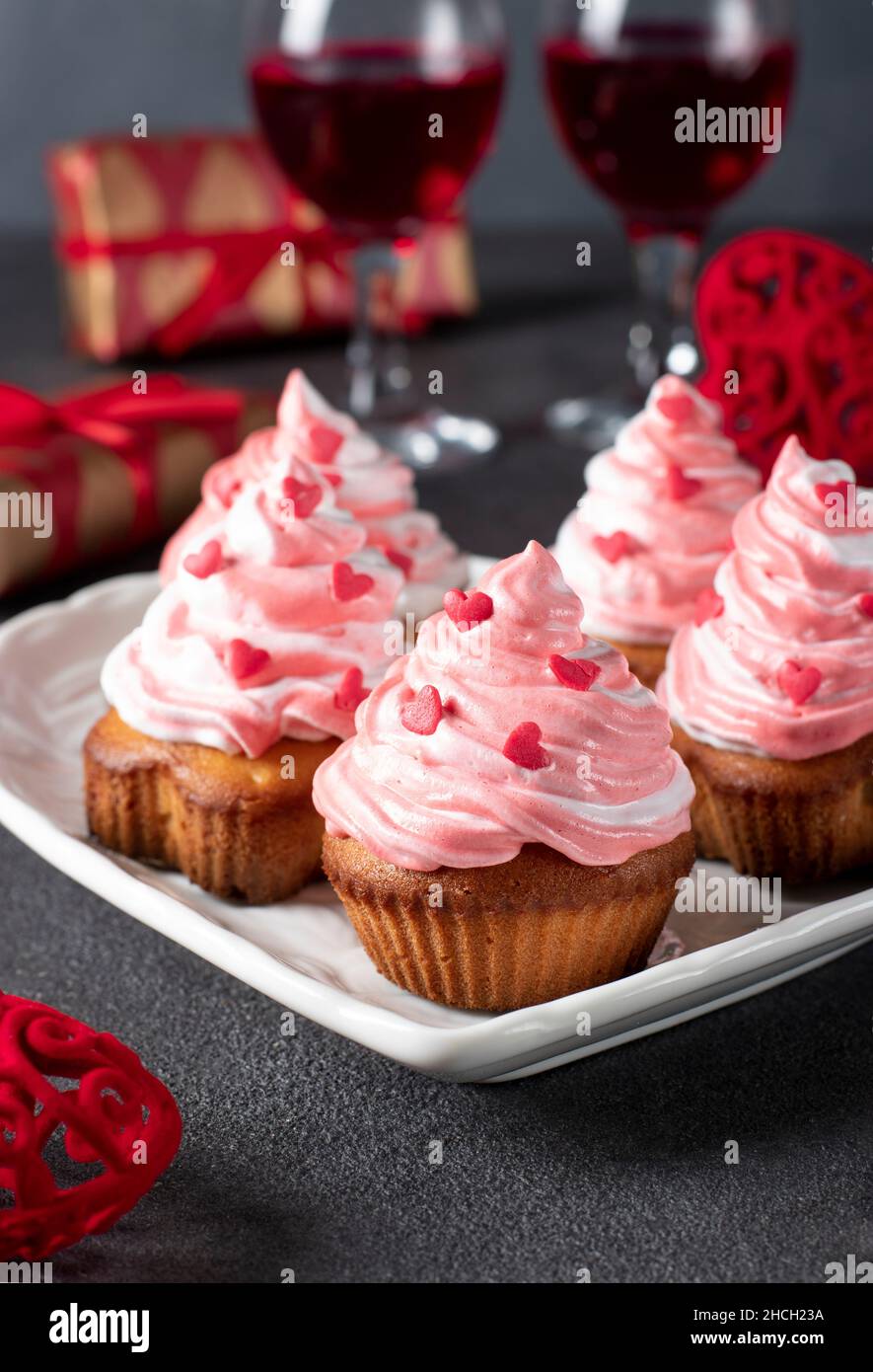 Petits gâteaux faits maison décorés de crème et de saupoudres en forme de coeur pour la Saint-Valentin sur fond gris, format vertical Banque D'Images