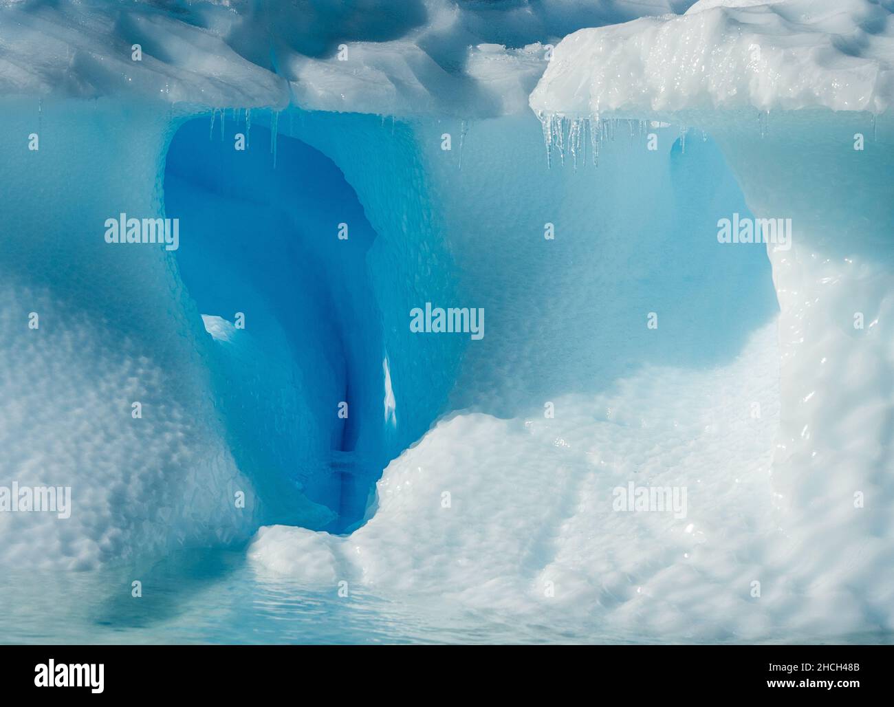 Photographie de paysage d'un iceberg avec une arche entourée de glace bleue dans une formation de vagues à l'île Danco, en Antarctique Banque D'Images