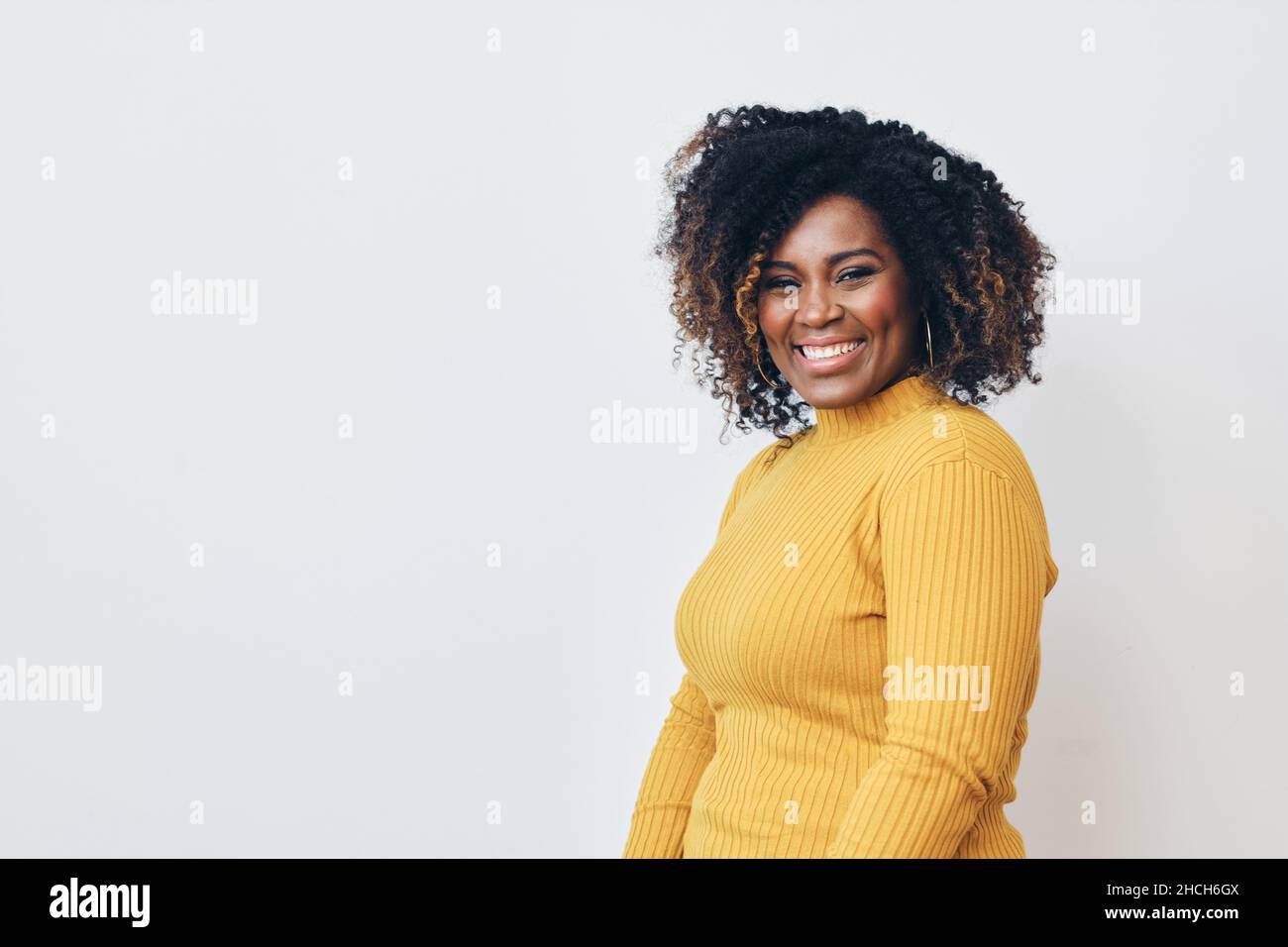 Femme joyeuse avec une coiffure frisée sur fond blanc.Sourire.Regarder l'appareil photo Banque D'Images
