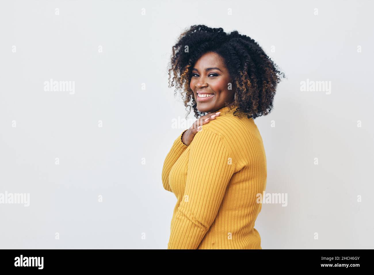 Femme joyeuse avec une coiffure frisée sur fond blanc.Sourire.Regarder l'appareil photo Banque D'Images