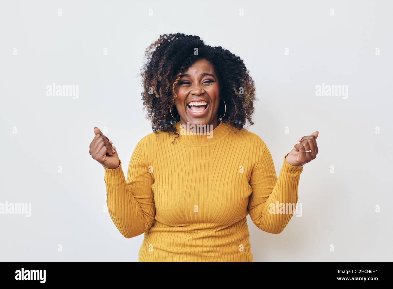 Femme joyeuse avec une coiffure frisée sur fond blanc.Sourire.Regarder l'appareil photo Banque D'Images
