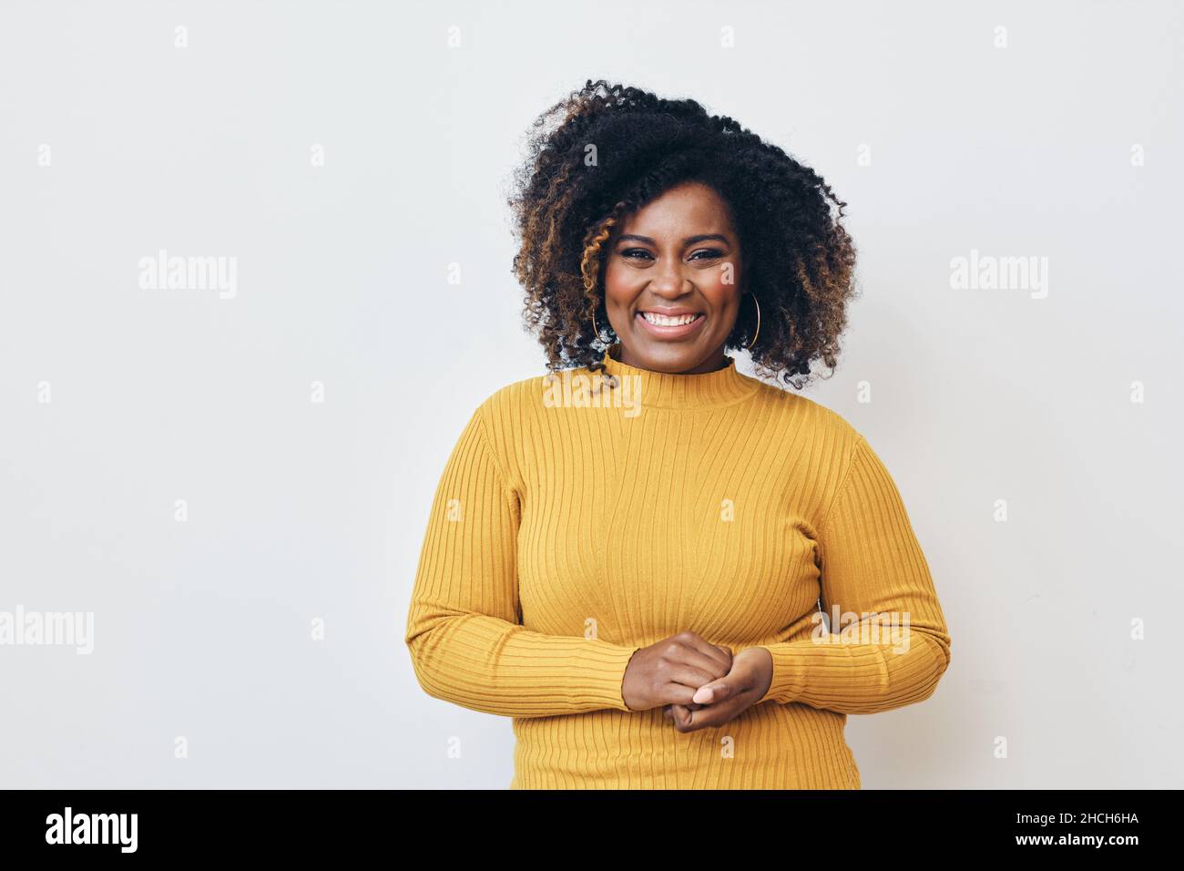 Femme joyeuse avec une coiffure frisée sur fond blanc.Sourire.Regarder l'appareil photo Banque D'Images