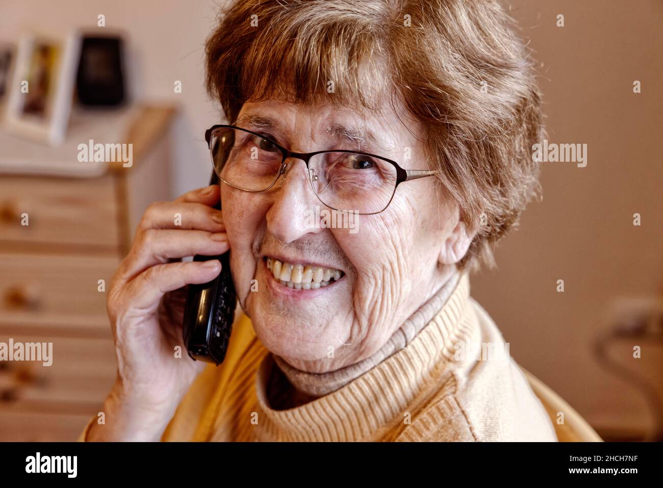 Senior à la maison riant au téléphone, Cologne, Rhénanie-du-Nord-Westphalie, Allemagne Banque D'Images