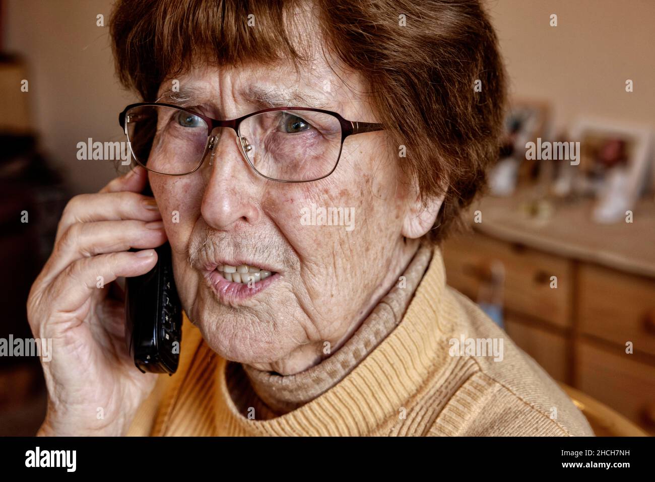 Senior à la maison tandis que le téléphone semble incertain, petit-fils tour, Cologne, Rhénanie-du-Nord-Westphalie, Allemagne Banque D'Images