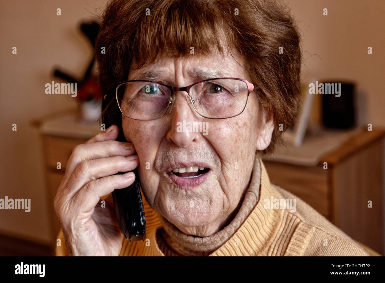 Senior à la maison tandis que le téléphone semble effrayé, petit-fils tour, Cologne, Rhénanie-du-Nord-Westphalie, Allemagne Banque D'Images
