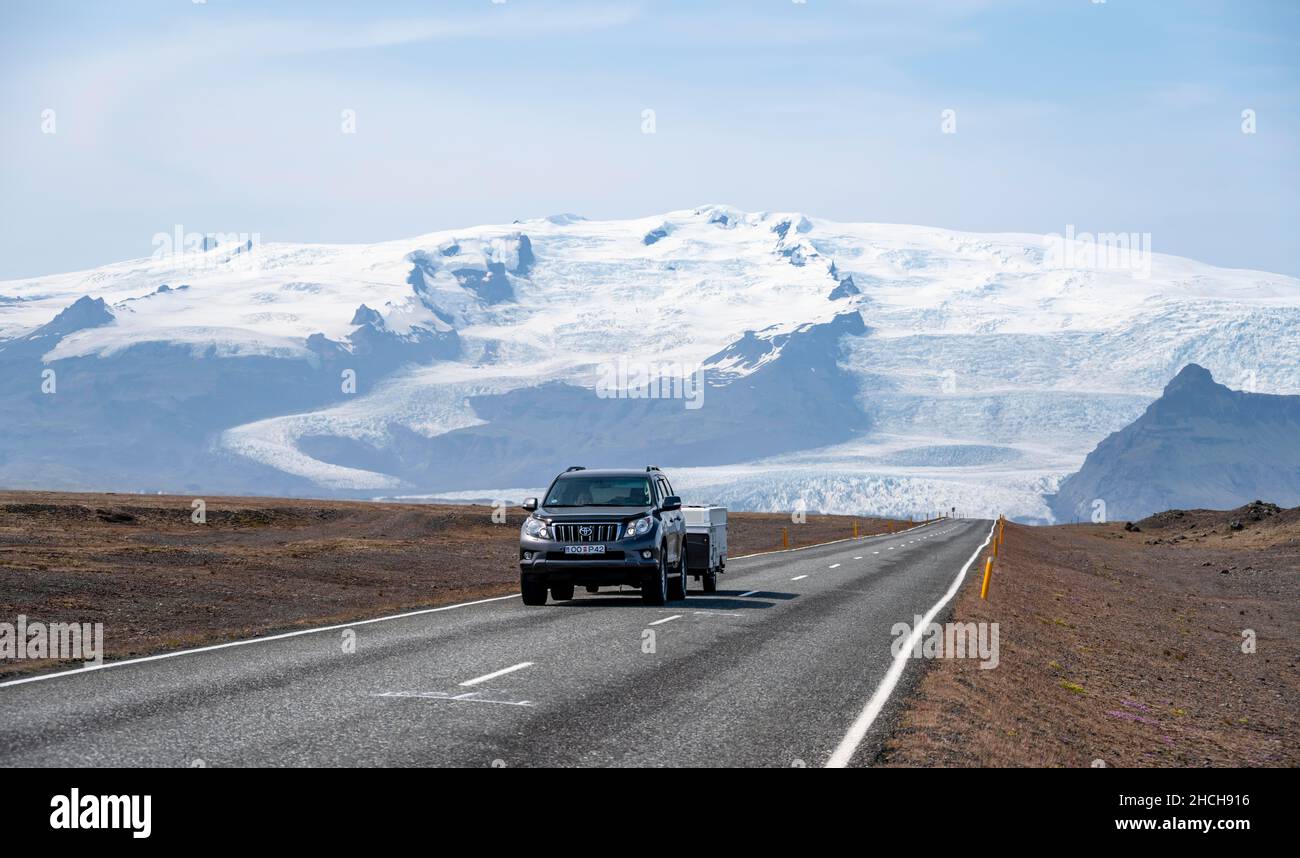 Voiture sur route de campagne, énorme glacier Vatnajoekull derrière, rocade, Islande Banque D'Images