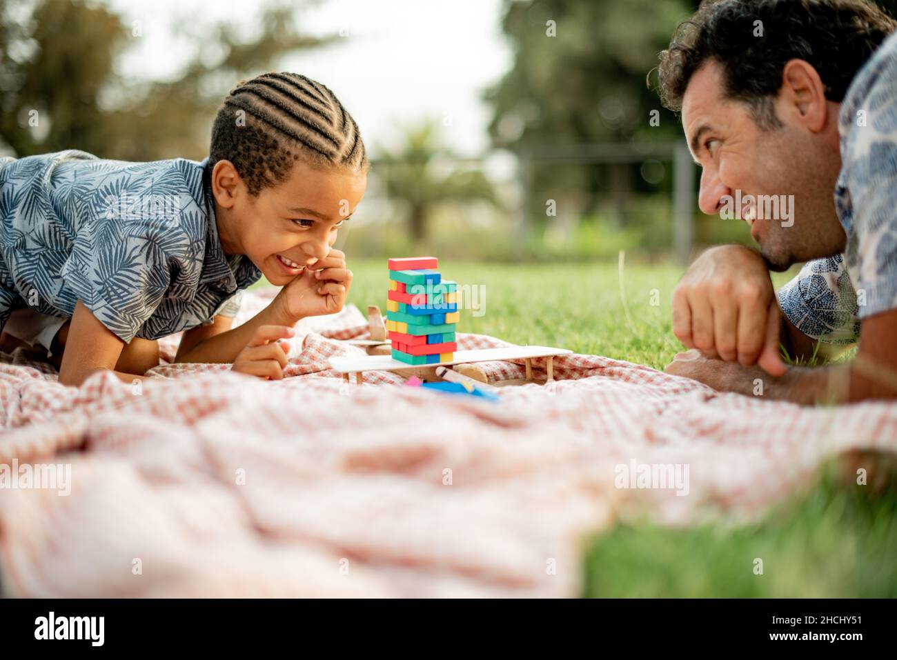 Joyeux père et fils multiethniques jouant un jeu de tour de bloc dans le parc Banque D'Images