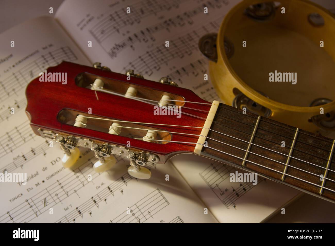 Image d'une guitare espagnole classique à côté d'un tambourin sur une partition musicale pour apprendre à jouer de la guitare. Banque D'Images