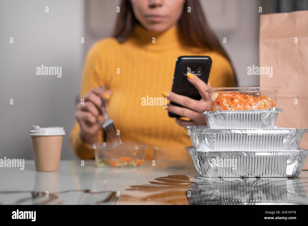 Portrait d'une femme se reposant à la maison à la table après le travail de bureau, en appréciant un dîner rapide dans la soirée.Menu de restauration rapide à emporter pour lire les actualités Banque D'Images