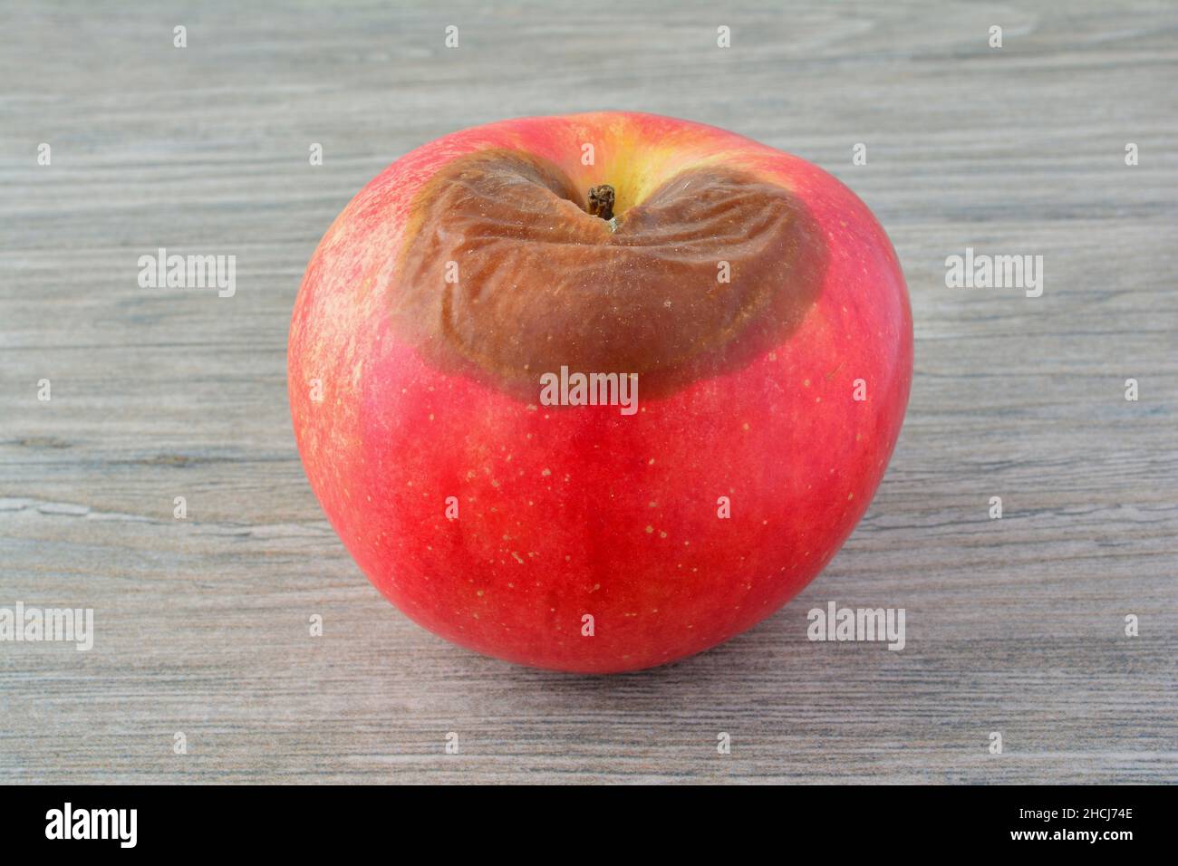 Pomme pourrie rouge sur fond en bois gris, vue rapprochée Banque D'Images