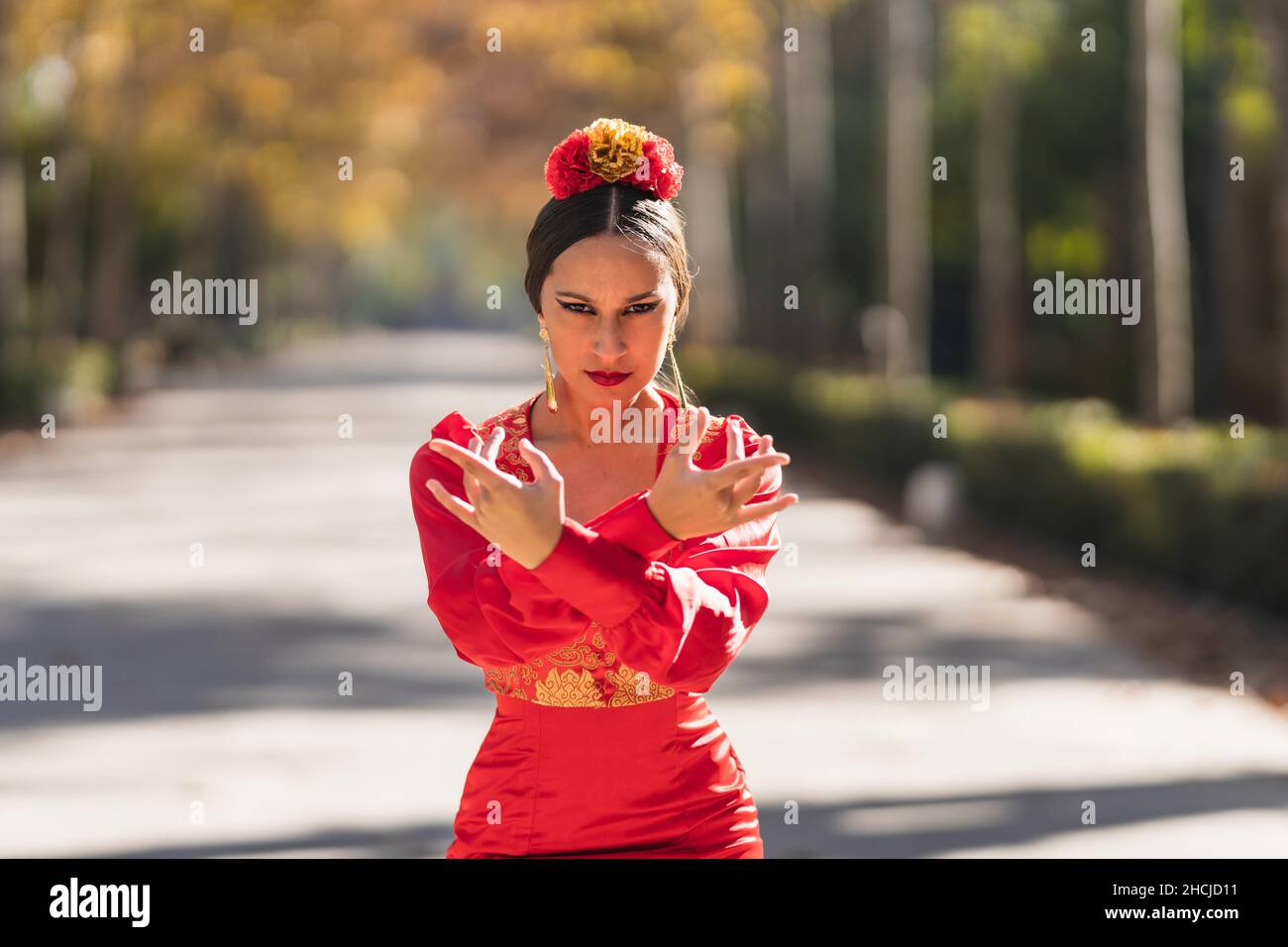Danseuse de flamenco en robe rouge avec des œillets sur sa tête dansant à l'extérieur Banque D'Images