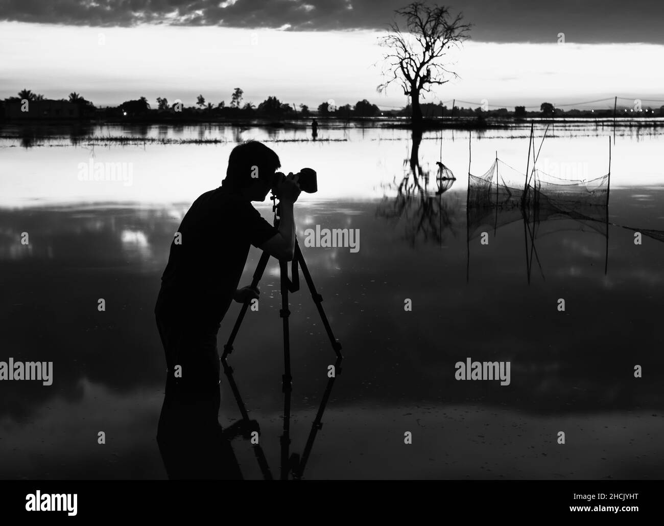 Silhouette d'un photographe qui chasse des photos dans les zones humides au coucher du soleil, capturant la vie rurale idyllique à Tay Ninh, Vietnam Banque D'Images