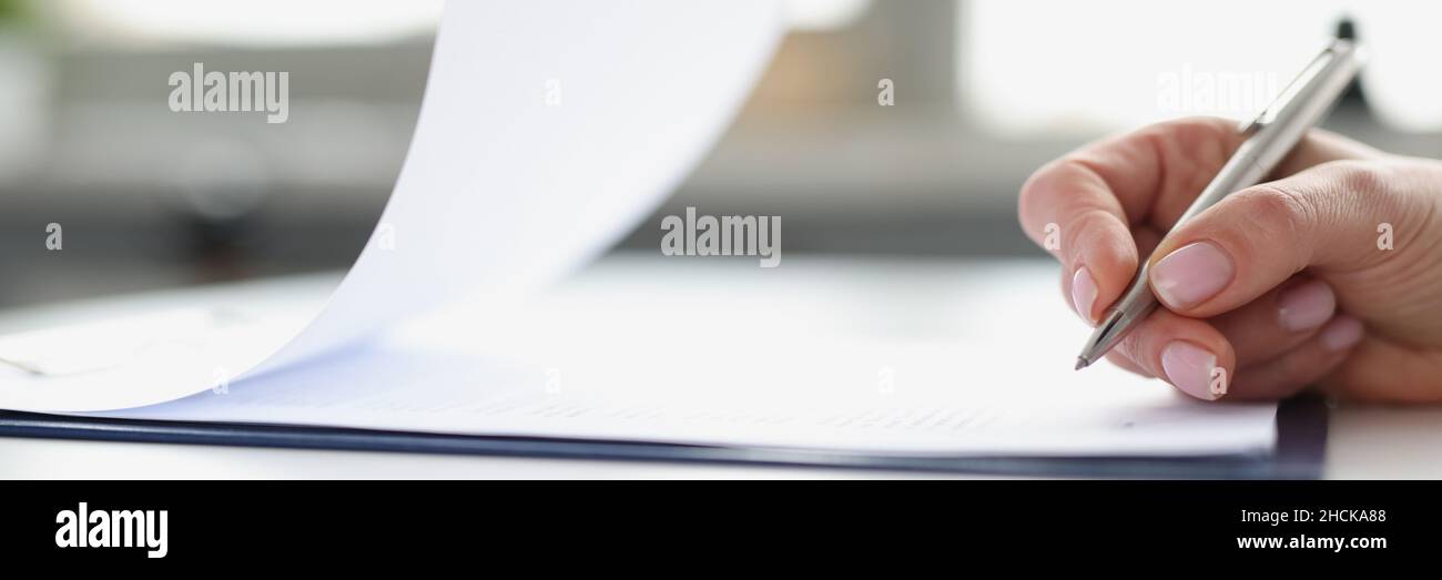 Une femme signe à la main des documents sur le presse-papiers avec un stylo à bille de gros plan Banque D'Images