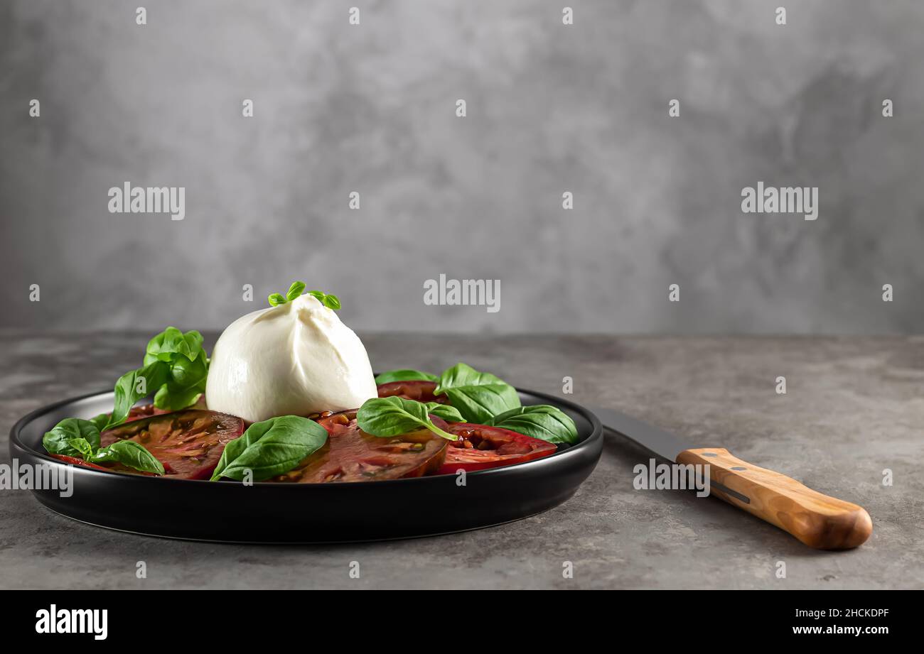 Fromage bisons burrata servi avec des tomates fraîches et des feuilles de basilic. Banque D'Images