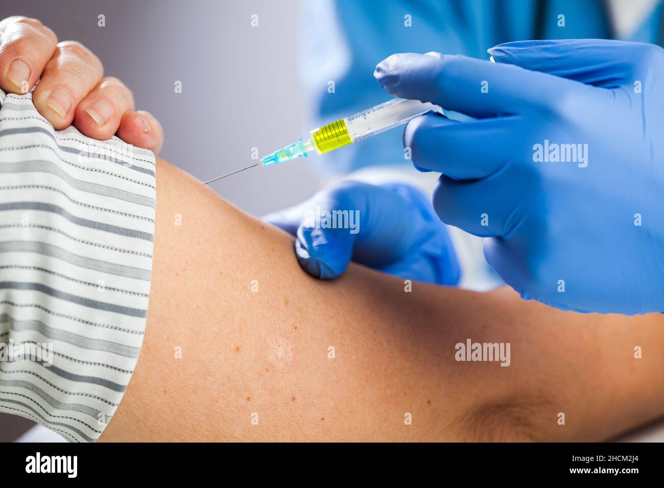 Injection de vaccin Covid-19, médecin portant des gants bleus tenant une seringue donnant un jab à une patiente âgée dans un hôpital ou une clinique,prévention Banque D'Images