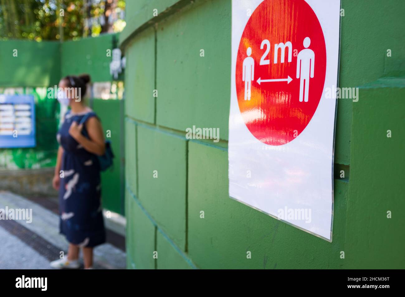 Panneau rouge fixé au mur vert informant les gens de garder une distance sociale de 2 mètres en raison de la pandémie de COVID-19, prévention et protection contre le coronavirus Banque D'Images