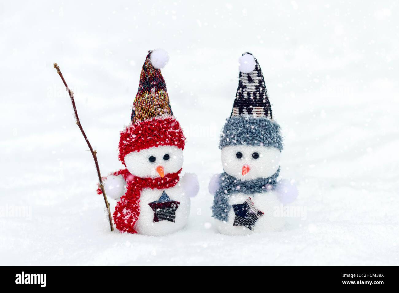 Joyeux noël et bonne année carte de voeux avec espace copie deux petits bonshommes de neige heureux en rouge, bleu casquette et écharpe debout dans le fond de neige d'hiver Banque D'Images