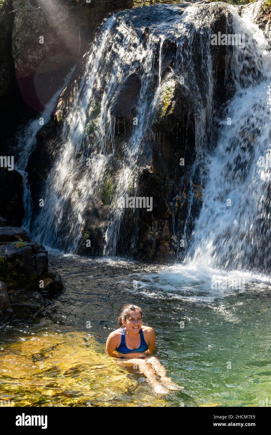 Jeune randonneur femelle ayant un bain dans la rivière de montagne par une petite cascade dans la montagne de Rila, Bulgarie Banque D'Images