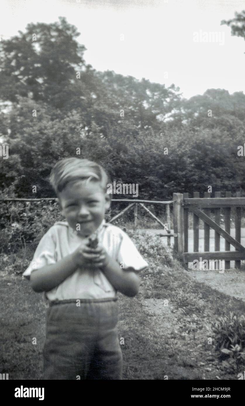 Jeune garçon caucasien âgé de 4 ans jouant dans le jardin avec un fusil à jouets 1956 Banque D'Images