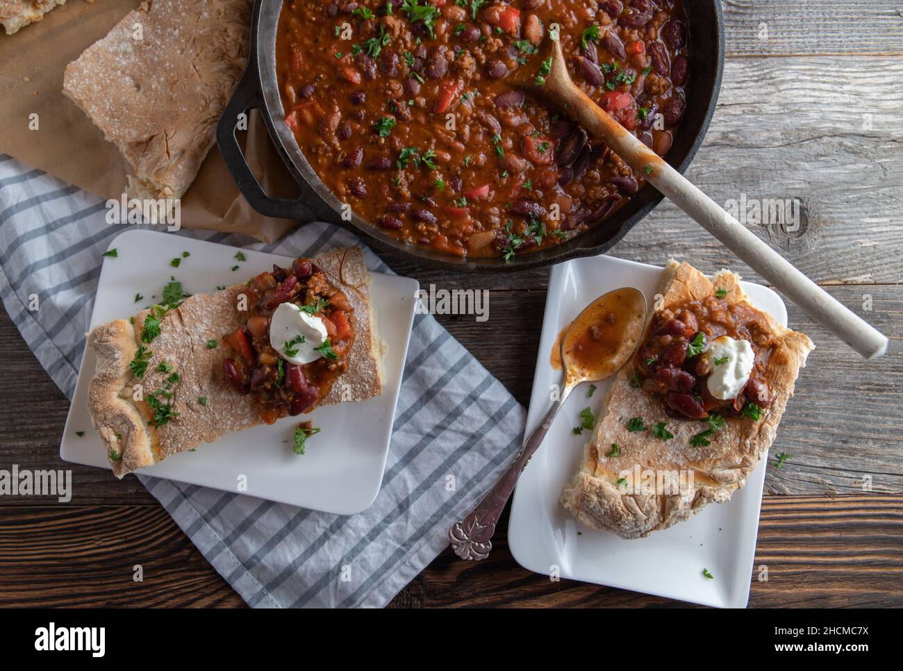 Ragoût de pain. Frais et fait maison, cuits avec des haricots et des légumes. Servi avec du pain plat sur une table en bois. Banque D'Images