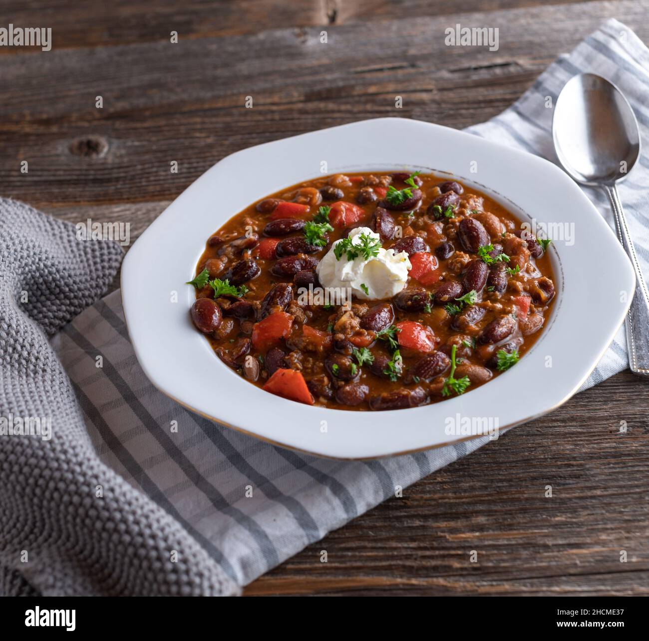 Assiette avec Chili frais cuit con carne isolée sur fond de table en bois. Surmontée de crème aigre Banque D'Images