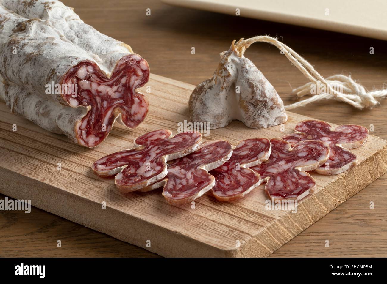 Saucisse sèche française en tranches, saucisson sec, sur une planche à découper en bois Banque D'Images