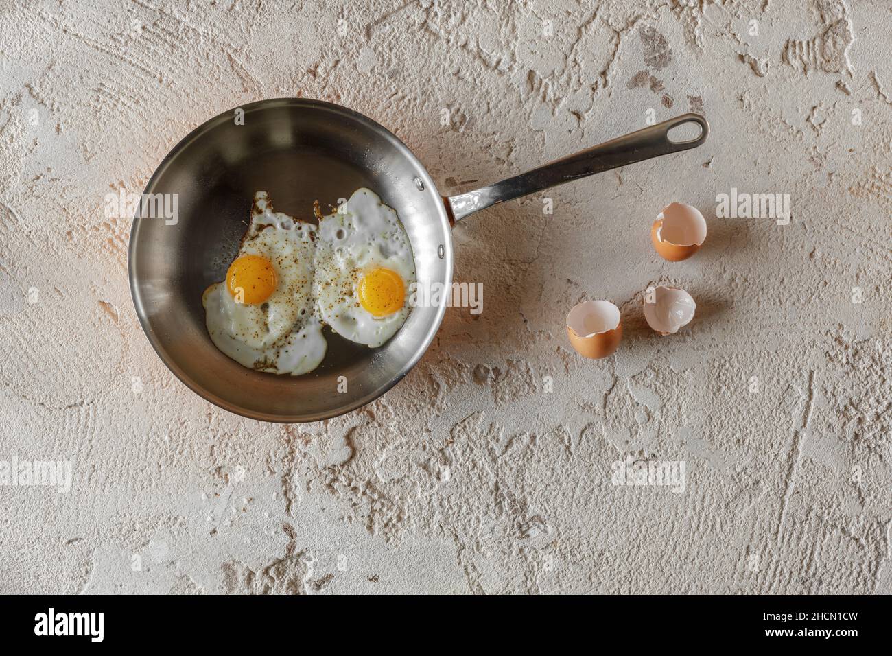Frit deux œufs dans une casserole de cuivre sur fond d'argile rugueux et texturée.Concept de petit déjeuner sain. Banque D'Images