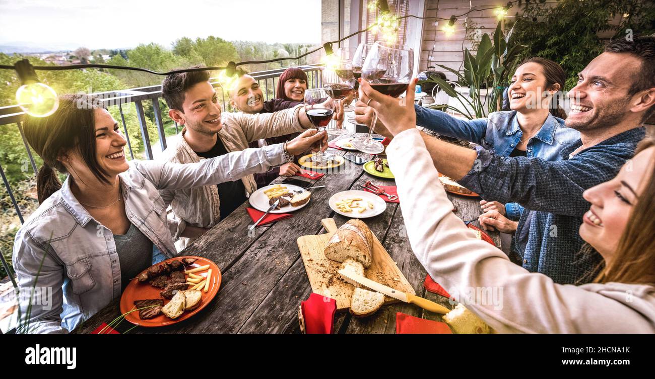 Les jeunes ont du plaisir à toaster le vin rouge ensemble au dîner dans la villa en plein air - heureux amis de manger un barbecue dans le patio du restaurant Banque D'Images