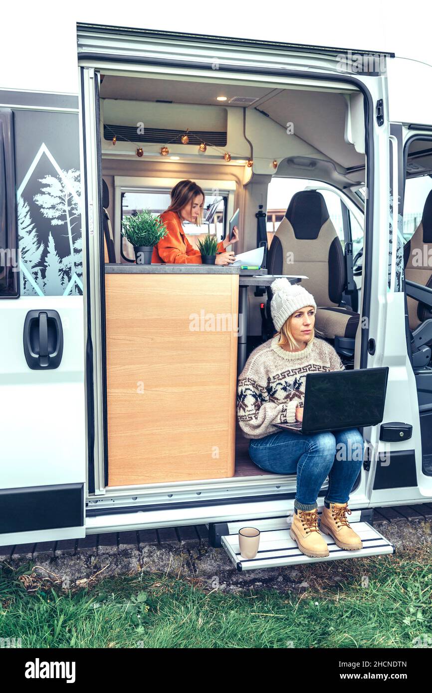 Femme de télétravail assise à la porte d'une camionnette de camping Banque D'Images