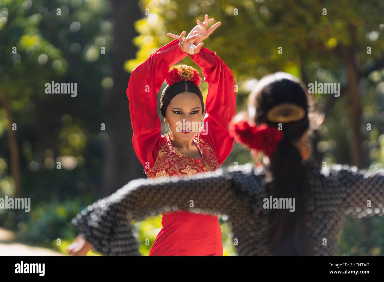 Deux femmes en robe flamenco dansant face à face dans un parc Banque D'Images