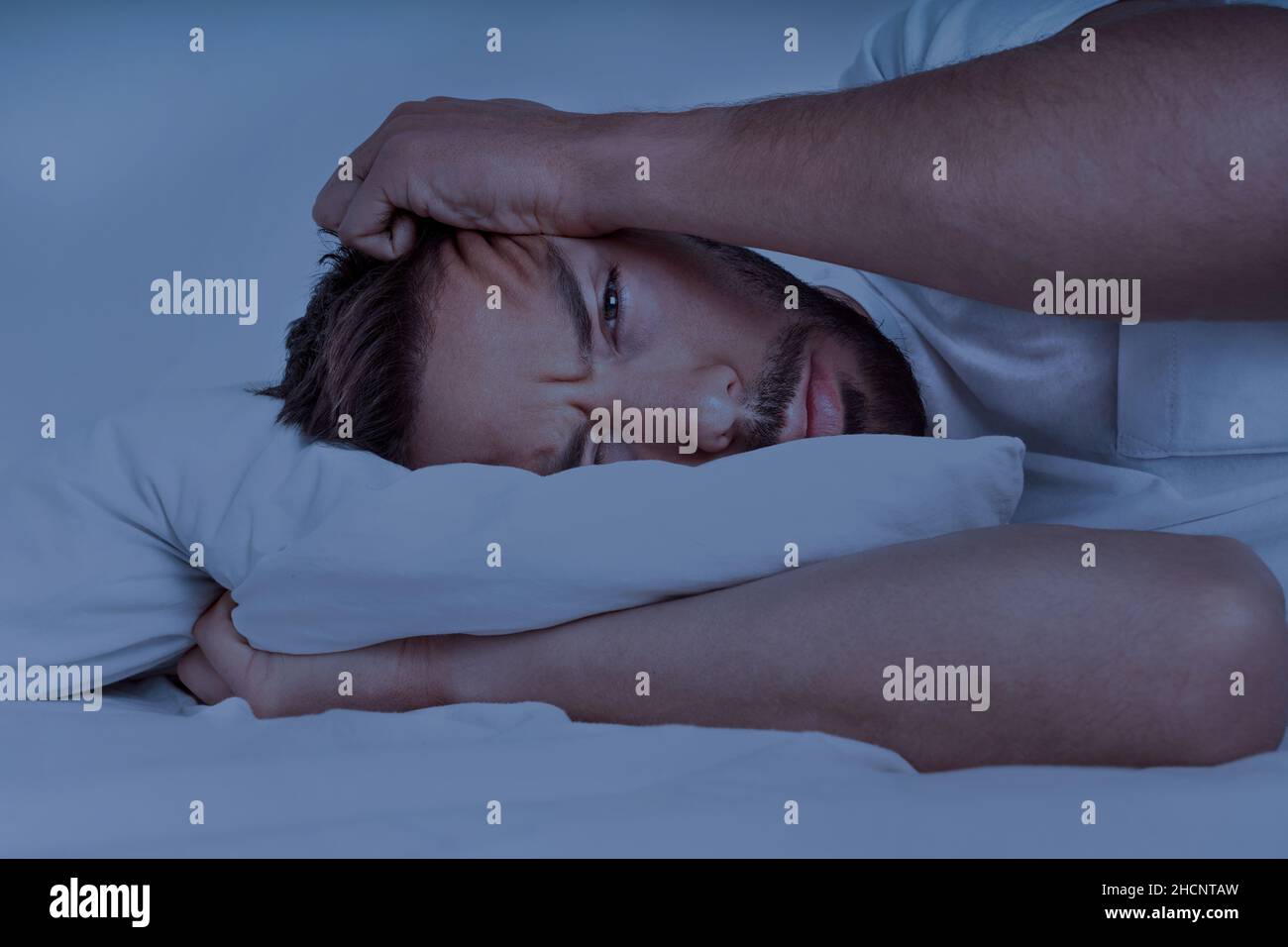 Jeune homme allongé dans le lit et essayant de dormir, ne peut pas dormir.Homme souffrant d'insomnie, de problèmes de sommeil ou de troubles du sommeil. Banque D'Images