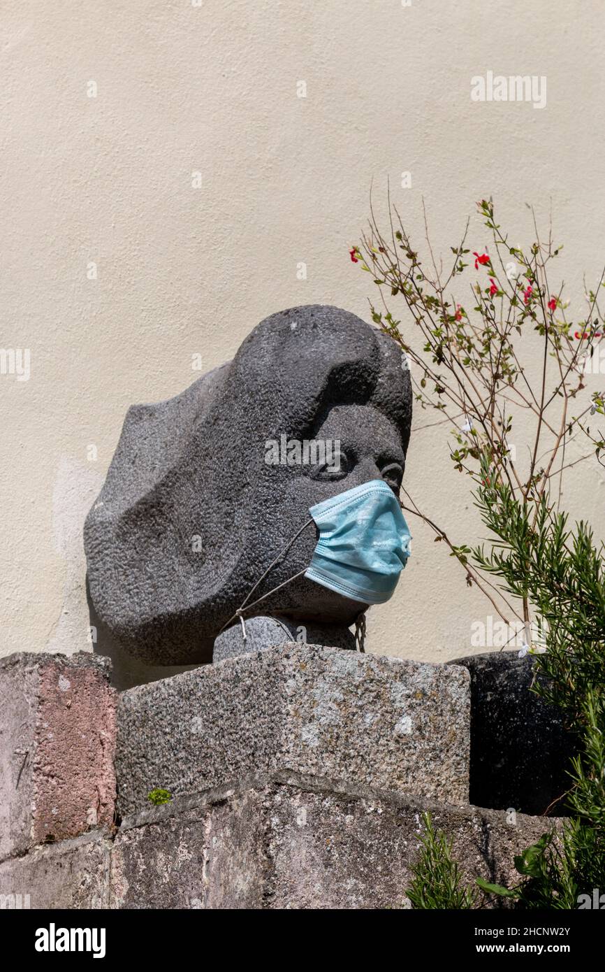 La sculpture en pierre de la tête d'une femme portant un masque facial pendant la pandémie de Covid.Cawsand, Cornwall, Royaume-Uni Banque D'Images